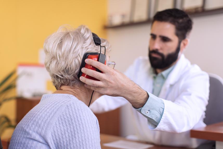 An audiologist putting headphones on a patient