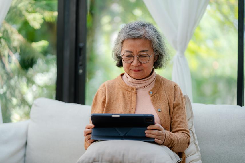 A woman sitting on a couch and looking at a tablet