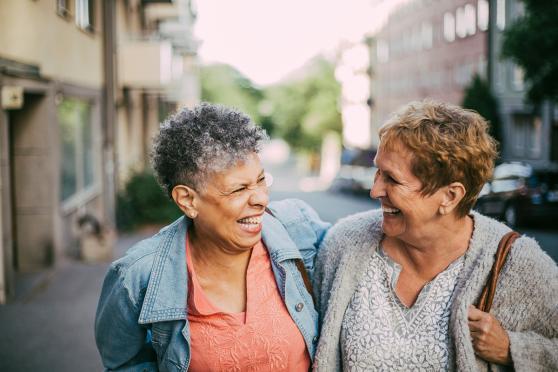 Two women laughing together, walking outside