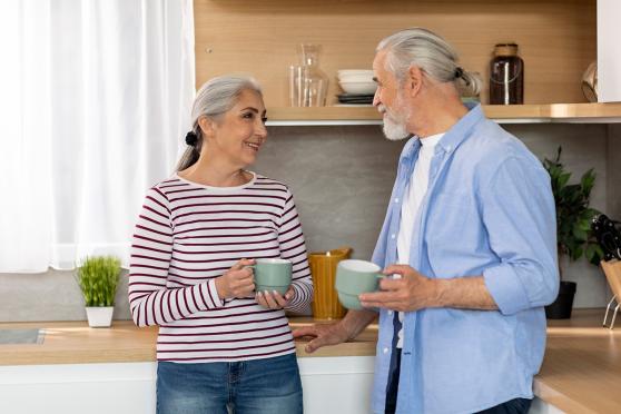 A couple talking in a kitchen, both holding mugs