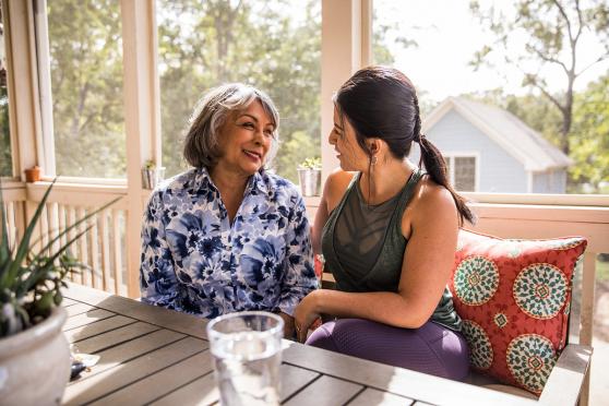 Senior adult and daughter laughing outside on a patio