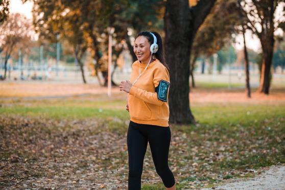 Woman running outside with headphones on, smiling