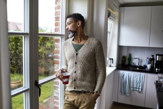 Man holding a mug, gazing out of a window